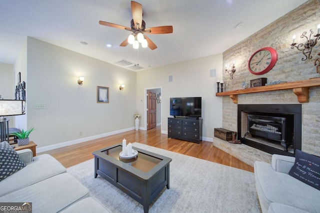 living room with light wood finished floors, ceiling fan, a fireplace, and baseboards