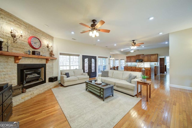 living room with light wood finished floors, a fireplace, baseboards, and recessed lighting