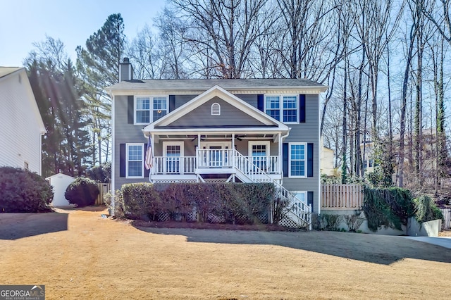 view of front of home with a chimney, a porch, stairway, a front yard, and driveway