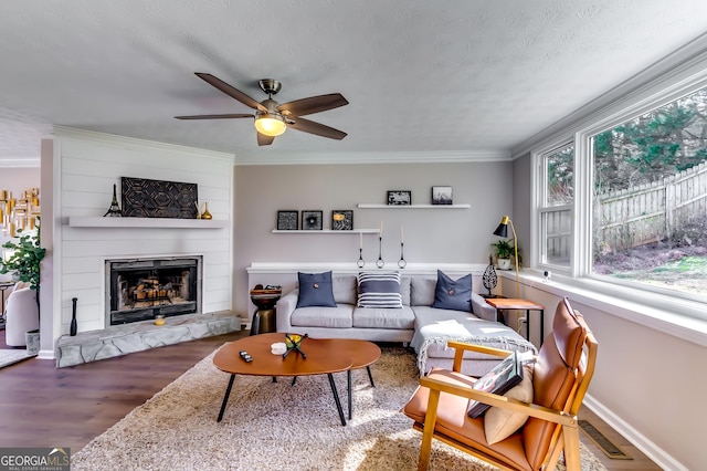 living area with a large fireplace, visible vents, wood finished floors, crown molding, and a textured ceiling