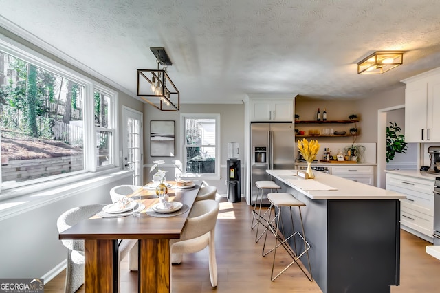 kitchen featuring a kitchen island, white cabinetry, light countertops, and stainless steel refrigerator with ice dispenser