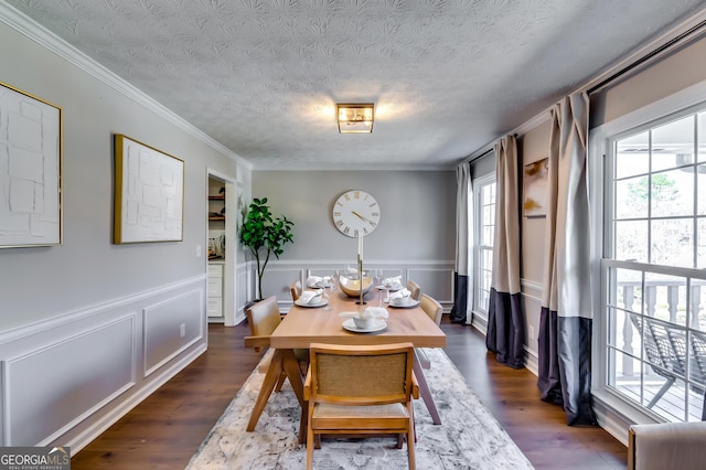 dining area featuring dark wood-style floors, crown molding, a textured ceiling, and a wainscoted wall