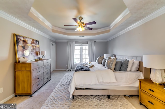 bedroom featuring ceiling fan, light carpet, baseboards, ornamental molding, and a tray ceiling