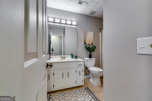 bathroom featuring a textured ceiling, toilet, vanity, and visible vents