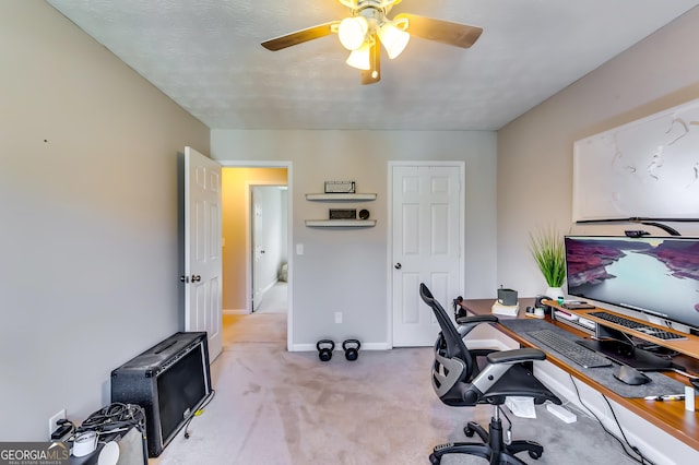 office area featuring light carpet, a ceiling fan, and baseboards