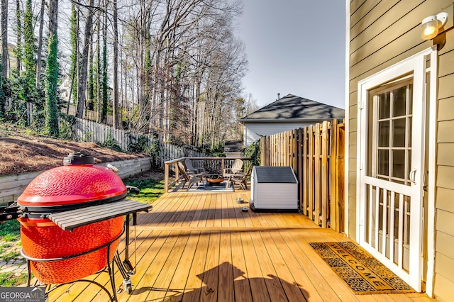 deck with an outdoor fire pit, a fenced backyard, and area for grilling