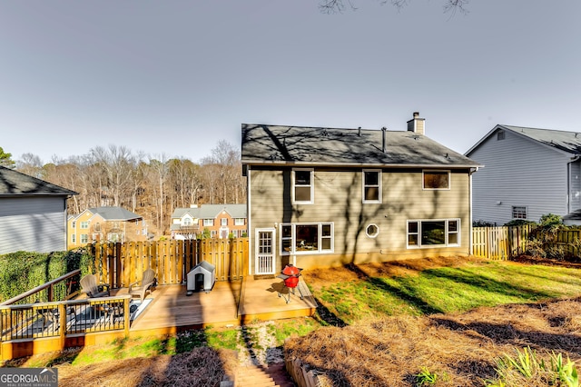 back of house featuring a chimney, fence, a lawn, and a wooden deck