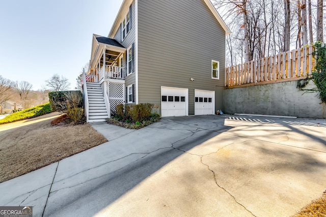 view of side of home with a garage, driveway, and stairway