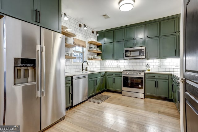 kitchen featuring green cabinets, stainless steel appliances, open shelves, and light countertops