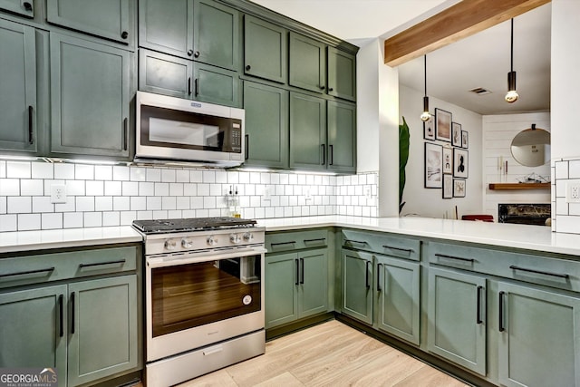 kitchen with green cabinetry, decorative light fixtures, stainless steel appliances, light countertops, and backsplash