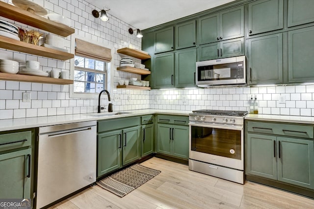 kitchen featuring green cabinets, light countertops, appliances with stainless steel finishes, and a sink