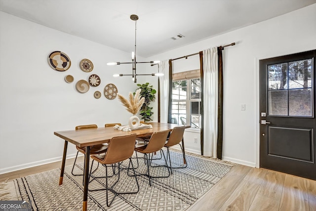 dining space with light wood-style floors, visible vents, a notable chandelier, and baseboards