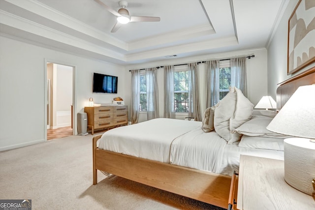 carpeted bedroom with ornamental molding, a raised ceiling, baseboards, and a ceiling fan