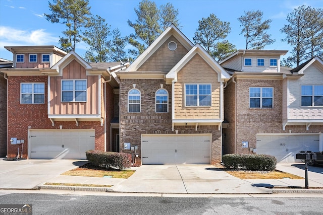 townhome / multi-family property with a garage, driveway, and brick siding