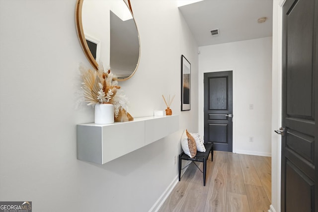 hallway with light wood-type flooring, baseboards, and visible vents