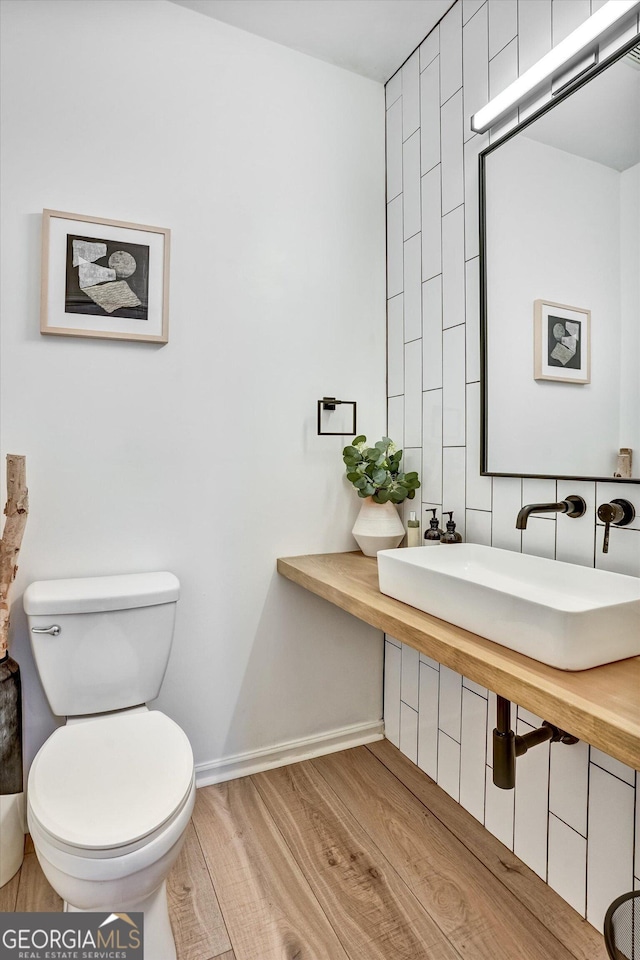 bathroom with baseboards, toilet, and wood finished floors