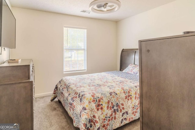 bedroom with light carpet, baseboards, visible vents, and a textured ceiling
