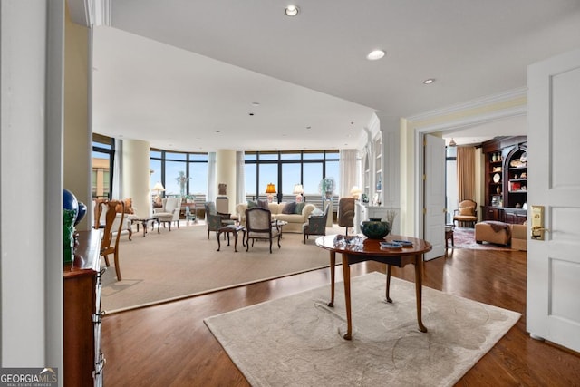 interior space featuring ornamental molding, recessed lighting, a wall of windows, and wood finished floors