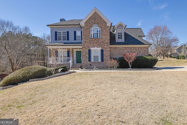 traditional-style house with covered porch, a front yard, and brick siding