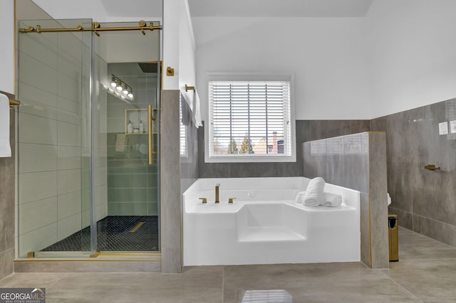 bathroom with a stall shower, tile patterned flooring, tile walls, and a bath