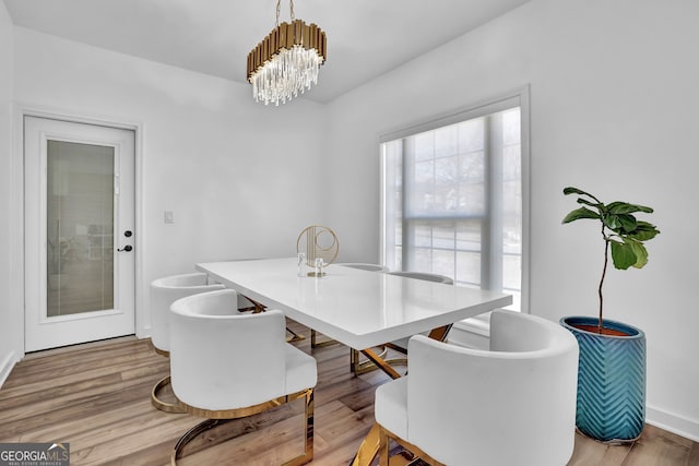 dining area with light wood-type flooring and a chandelier