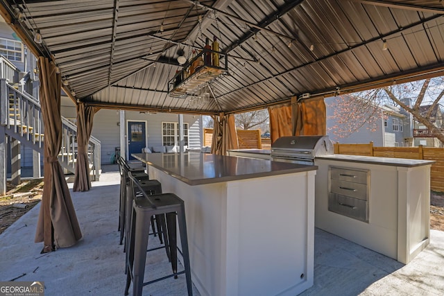 view of patio / terrace with exterior kitchen, outdoor wet bar, a grill, and fence