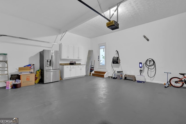 garage featuring a garage door opener and stainless steel refrigerator with ice dispenser