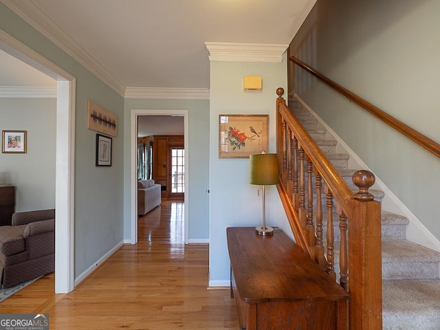 interior space with light wood-type flooring, stairs, baseboards, and crown molding