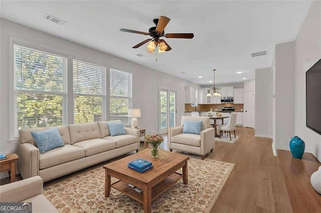 living area with a ceiling fan, recessed lighting, visible vents, and light wood-style floors