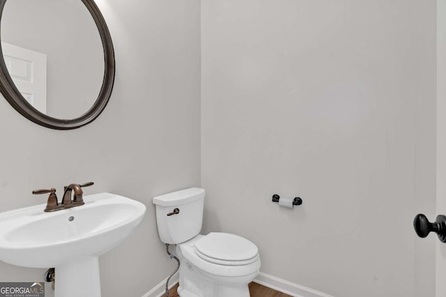 bathroom featuring baseboards, a sink, toilet, and wood finished floors