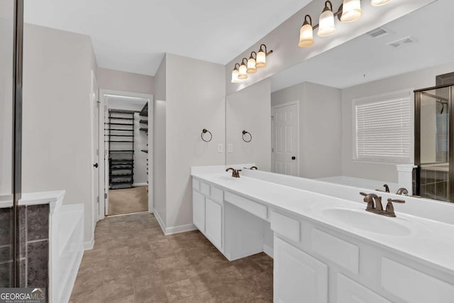 bathroom featuring a garden tub, double vanity, visible vents, a spacious closet, and a sink