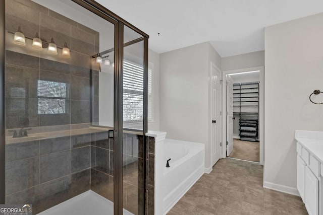 bathroom with a garden tub, vanity, baseboards, a spacious closet, and a shower stall