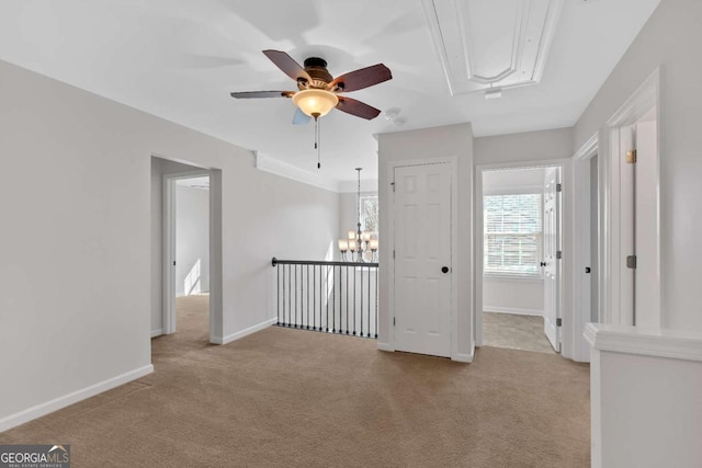 unfurnished room with attic access, light carpet, baseboards, and ceiling fan with notable chandelier