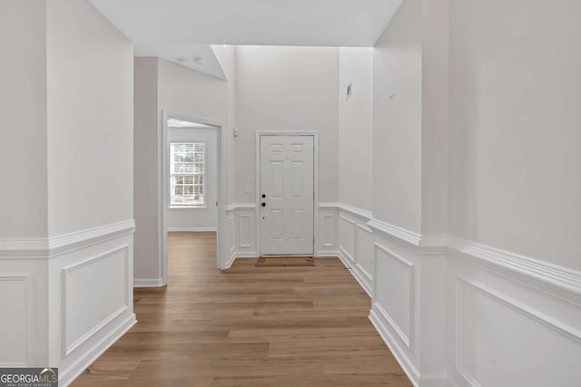 hallway featuring light wood-type flooring and a decorative wall