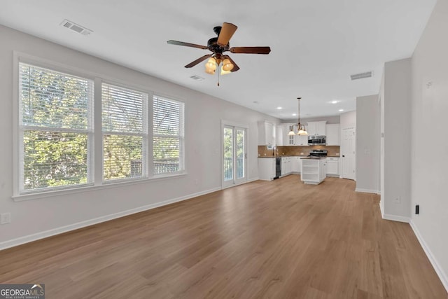 unfurnished living room featuring a ceiling fan, light wood-style flooring, visible vents, and baseboards