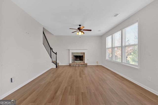 unfurnished living room with a fireplace, visible vents, baseboards, stairs, and light wood-type flooring