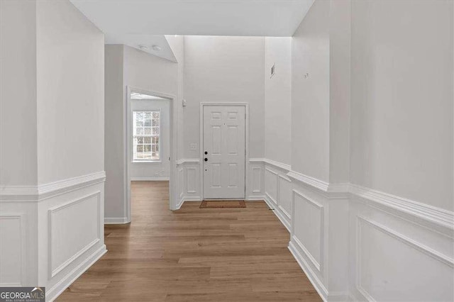 hallway featuring light wood-type flooring, visible vents, and a decorative wall