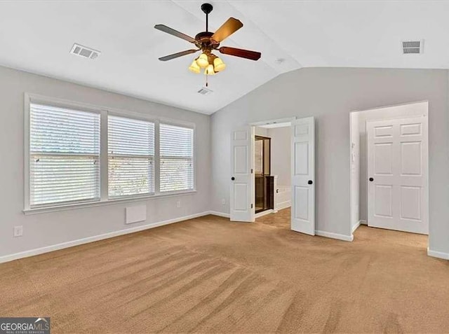 unfurnished bedroom featuring vaulted ceiling, baseboards, visible vents, and light colored carpet