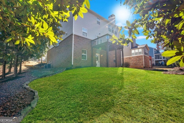 rear view of property featuring central AC unit, a lawn, and a balcony