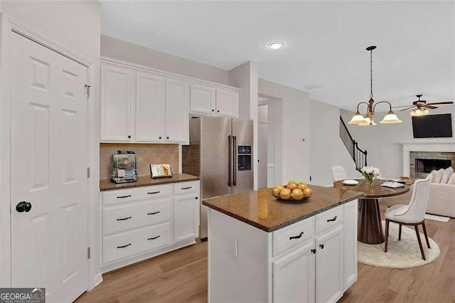 kitchen with high quality fridge, a kitchen island, open floor plan, light wood-type flooring, and white cabinetry