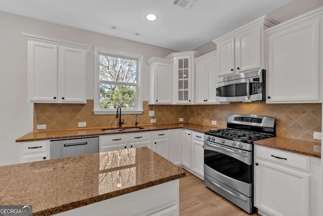 kitchen featuring glass insert cabinets, white cabinetry, appliances with stainless steel finishes, and a sink