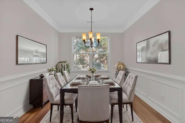 dining area featuring ornamental molding, a wainscoted wall, a notable chandelier, and wood finished floors