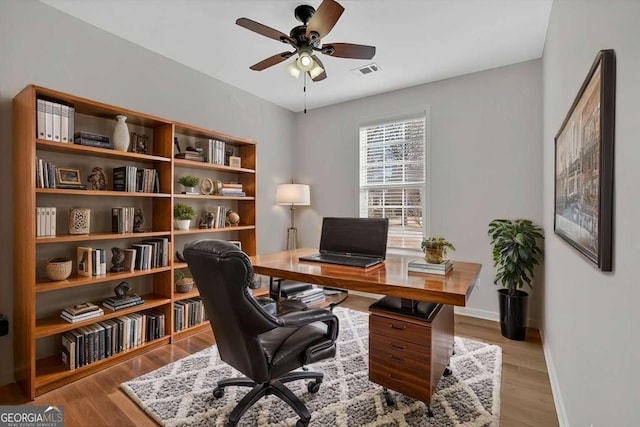 office featuring light wood-type flooring, visible vents, ceiling fan, and baseboards