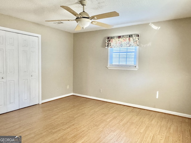 unfurnished bedroom featuring light wood-style floors, a closet, visible vents, and a textured ceiling