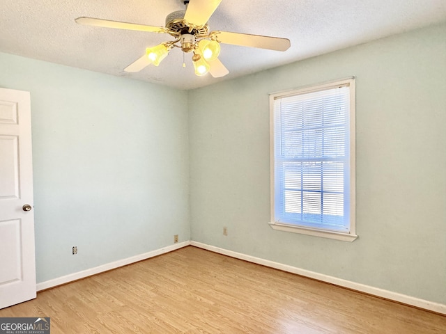 unfurnished room featuring light wood-type flooring, ceiling fan, baseboards, and a textured ceiling