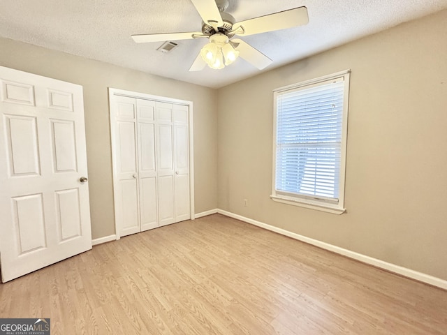 unfurnished bedroom featuring light wood finished floors, baseboards, visible vents, and a closet