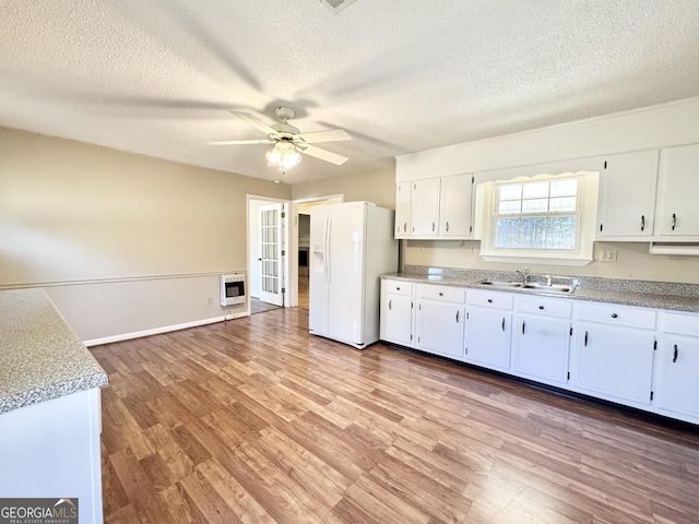 kitchen featuring white fridge with ice dispenser, light countertops, and white cabinets