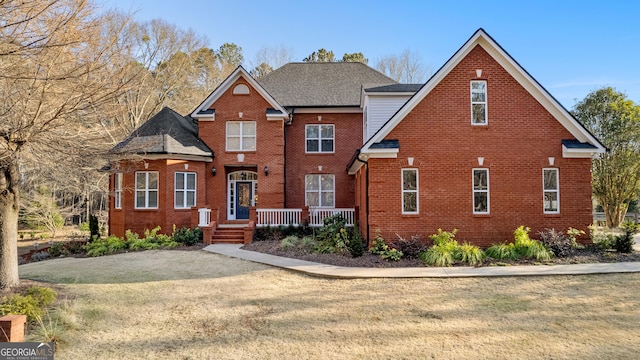 traditional home featuring brick siding, a front lawn, and a shingled roof