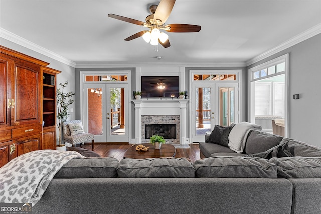 living area with a tiled fireplace, french doors, crown molding, and dark wood-style flooring