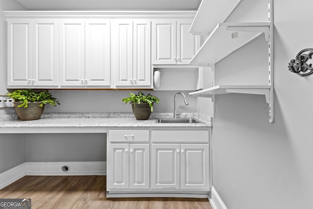 clothes washing area featuring a sink, baseboards, and wood finished floors